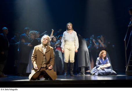 Theateraufführung mit Schauspielern in historischen Kostümen auf einer Bühne.