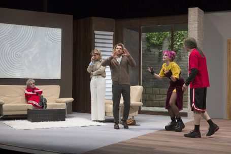 Szenenbild einer Theateraufführung mit vier Schauspielern in einem Wohnzimmer.