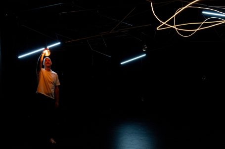 Eine Person hält ein Licht in der Dunkelheit, umgeben von leuchtenden Linien.